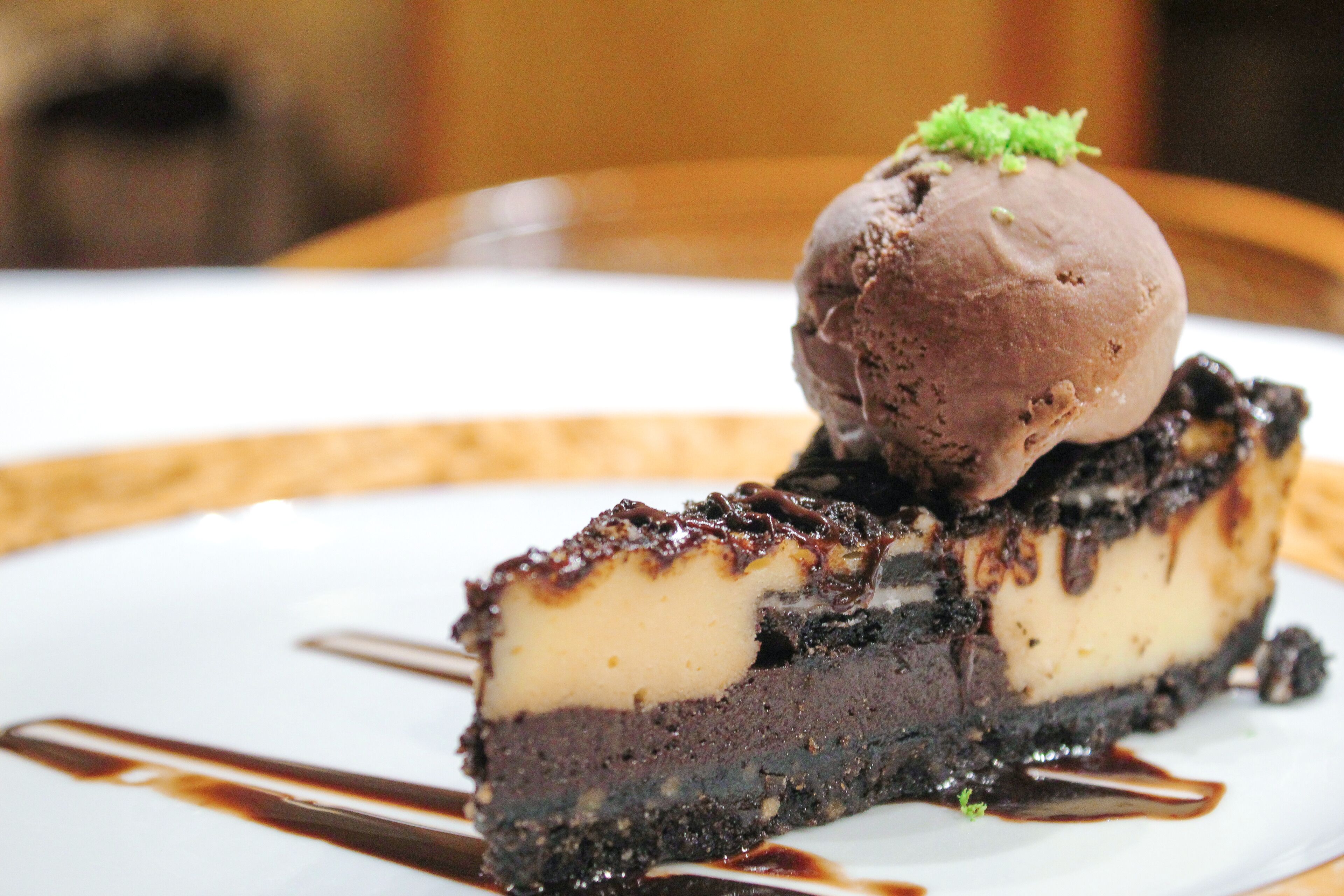 A dessert with a scoop of ice cream on top, served on a white plate with chocolate sauce drizzled around it.
