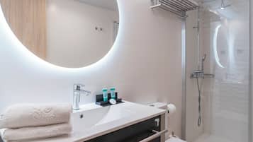 Une salle de bain moderne avec un grand miroir rond, un lavabo et une douche.