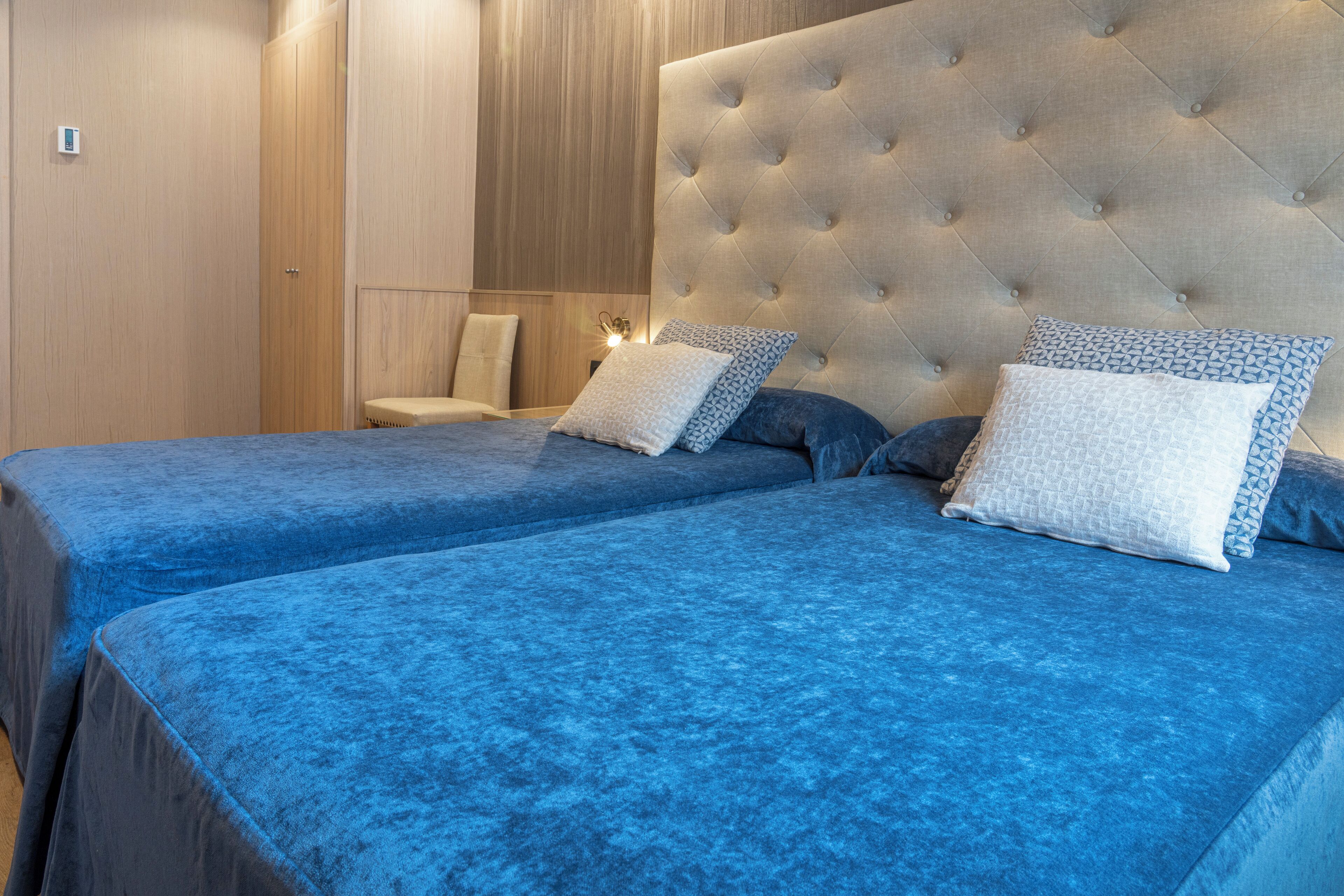Een hotelkamer met twee bedden, een gestapeld hoofdeinde en een houten paneelwand.
