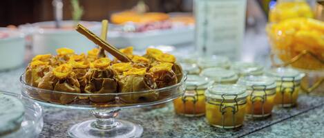 Uma mesa de buffet com diversos alimentos, incluindo um prato com fruta amarela e um pote de mel.