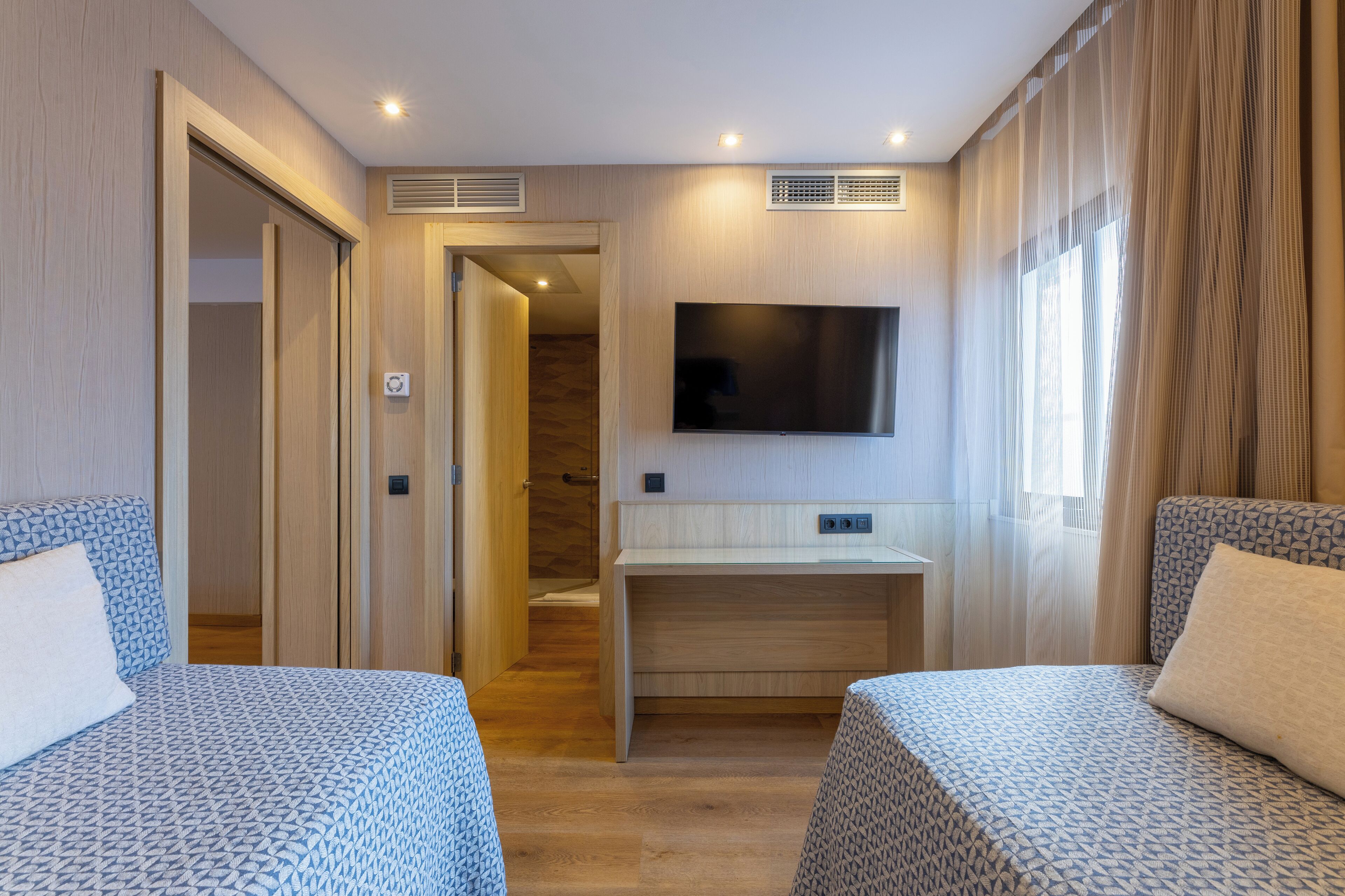 Una habitación de hotel con dos camas, televisión y escritorio.