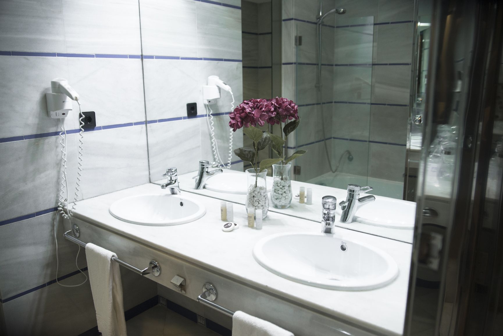 Un baño con dos lavamanos, un espejo y un perchero para toallas.