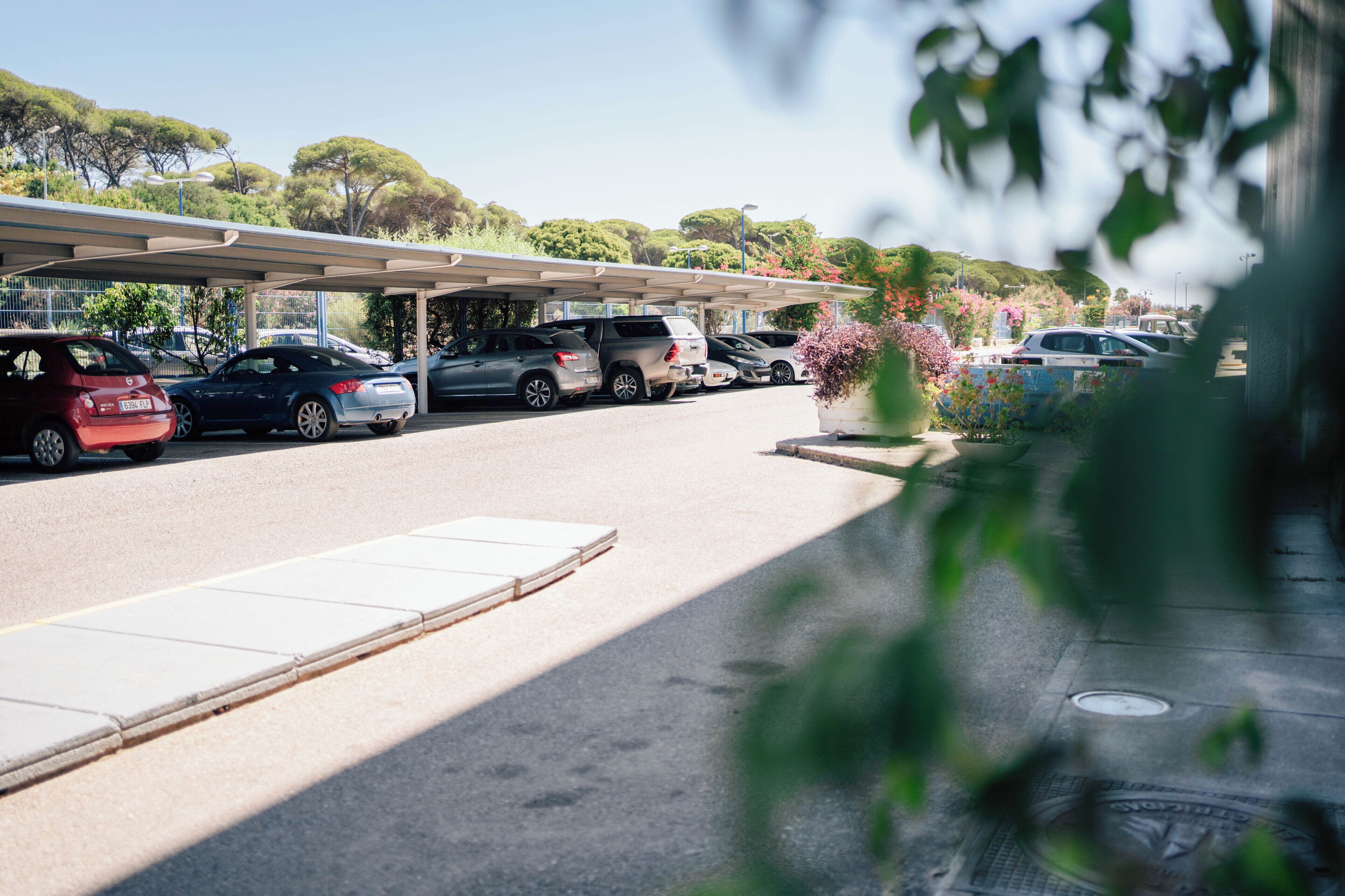 A parking area with multiple cars and a covered structure.