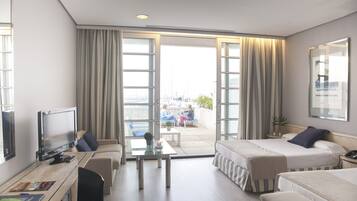A hotel room with two beds, a desk, a TV, and a balcony with a view.