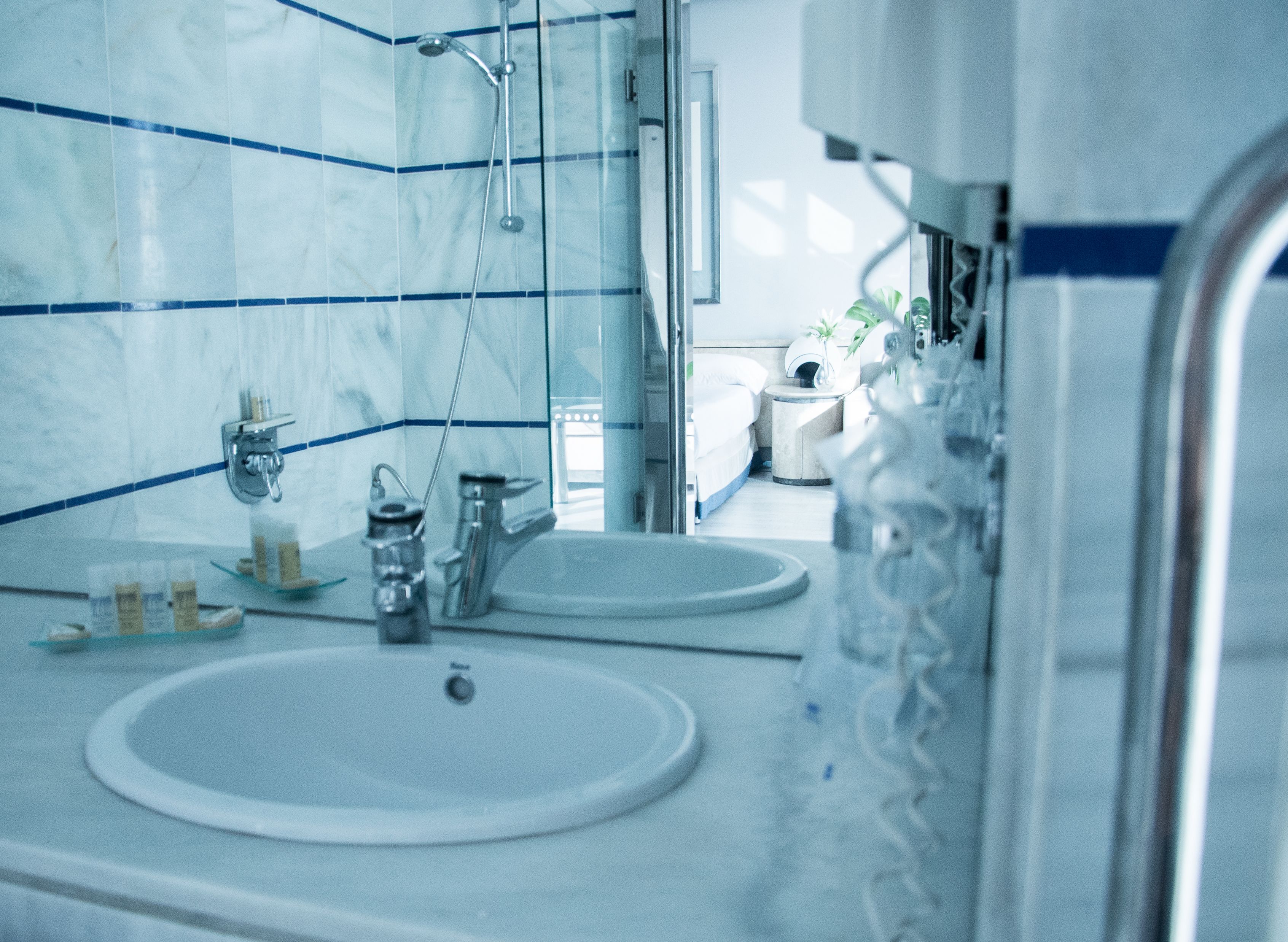 Ein modernes Badezimmer mit zwei Waschbecken, einer Dusche und einem Spiegel.