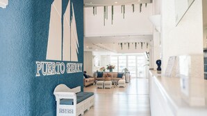 Un hall d’entrée avec un mur bleu, un comptoir d’accueil et des espaces d’attente.