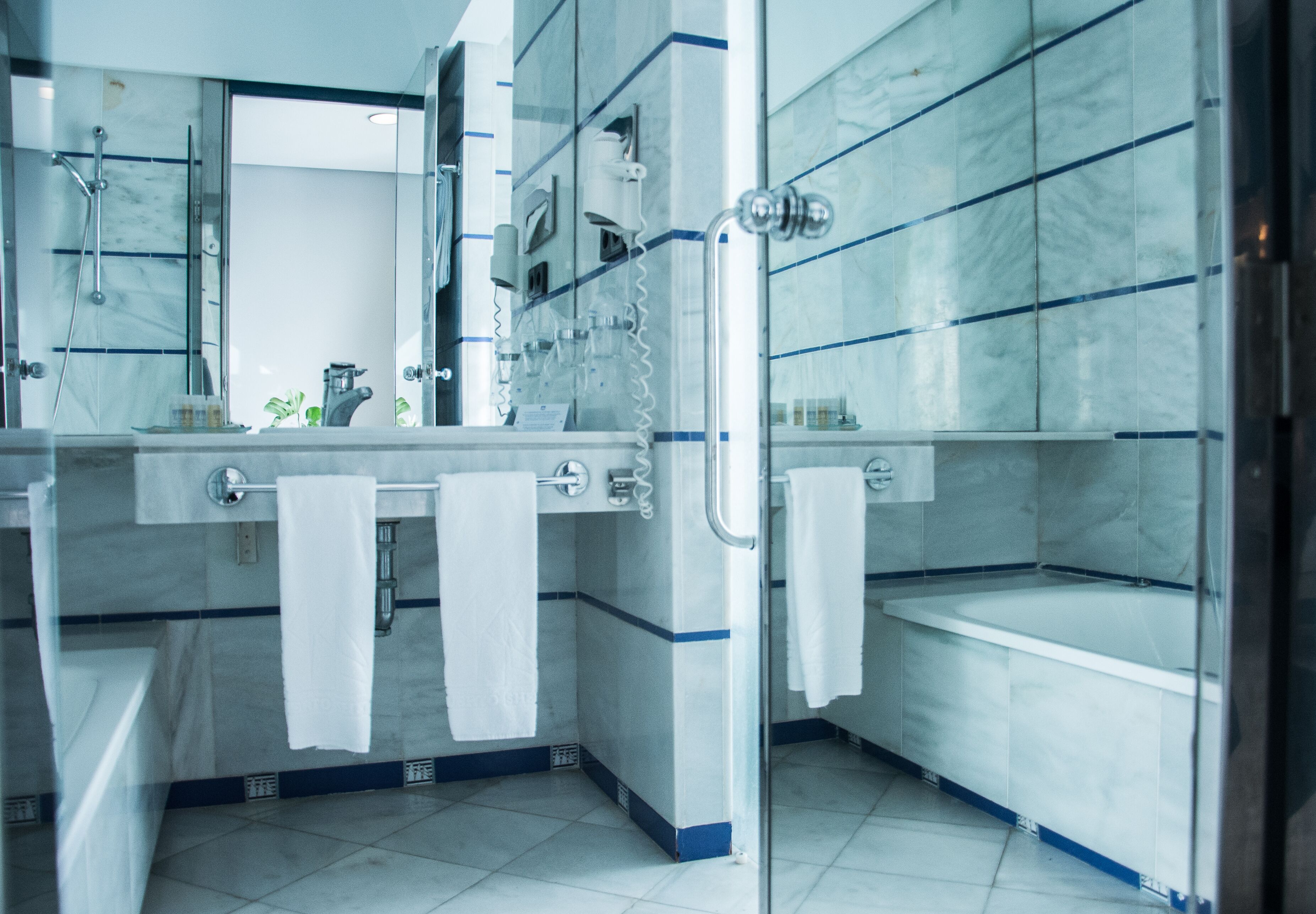 A modern bathroom with a glass shower enclosure, a large mirror, and a bathtub.