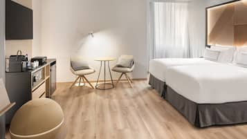 Een moderne hotelkamer met een groot bed, een bureau met een computer, een stoel, een ronde tafel en een groot raam met gordijnen.