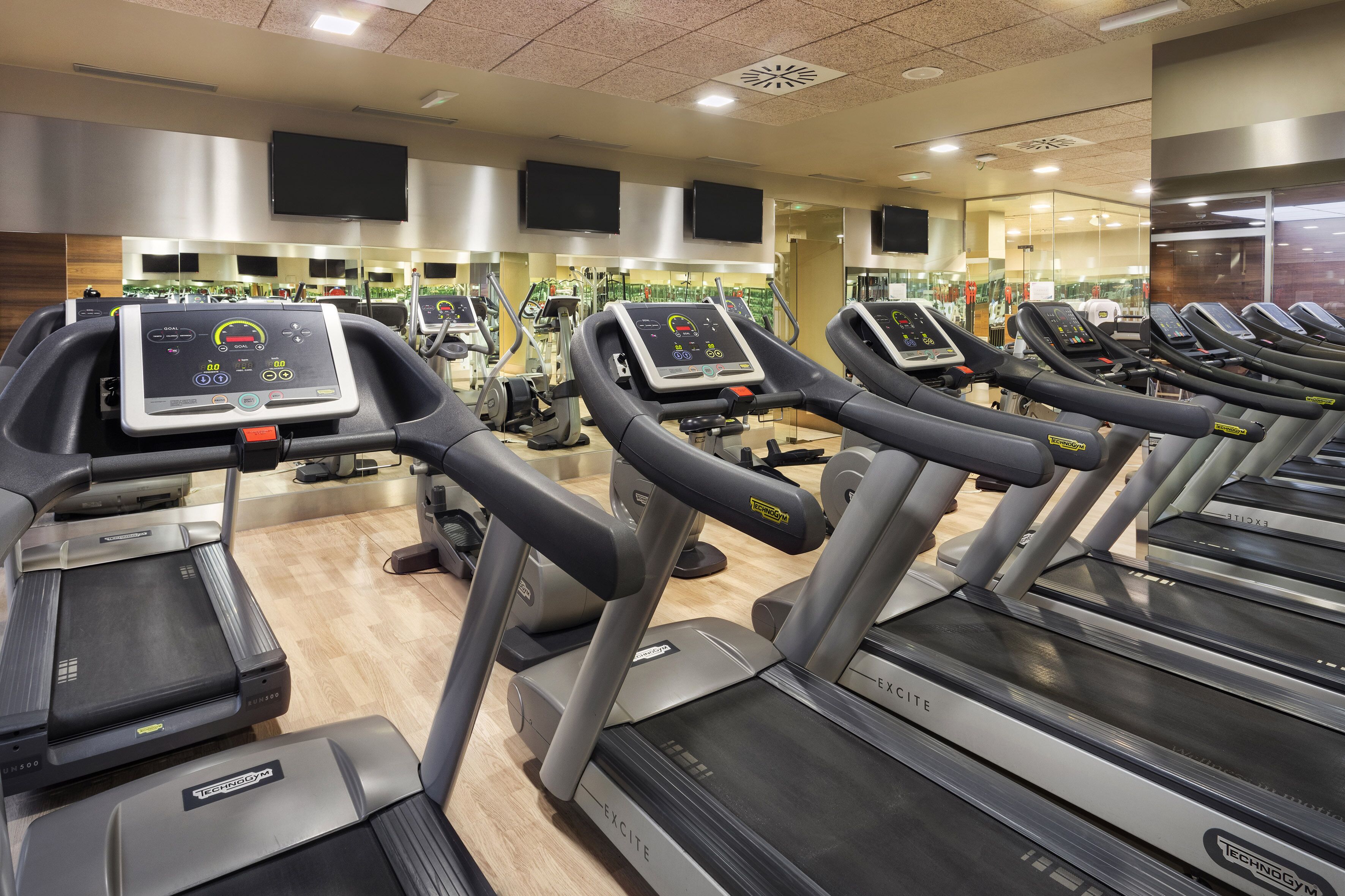 Un gimnasio con cintas de correr, equipo de ejercicio y un espejo grande.