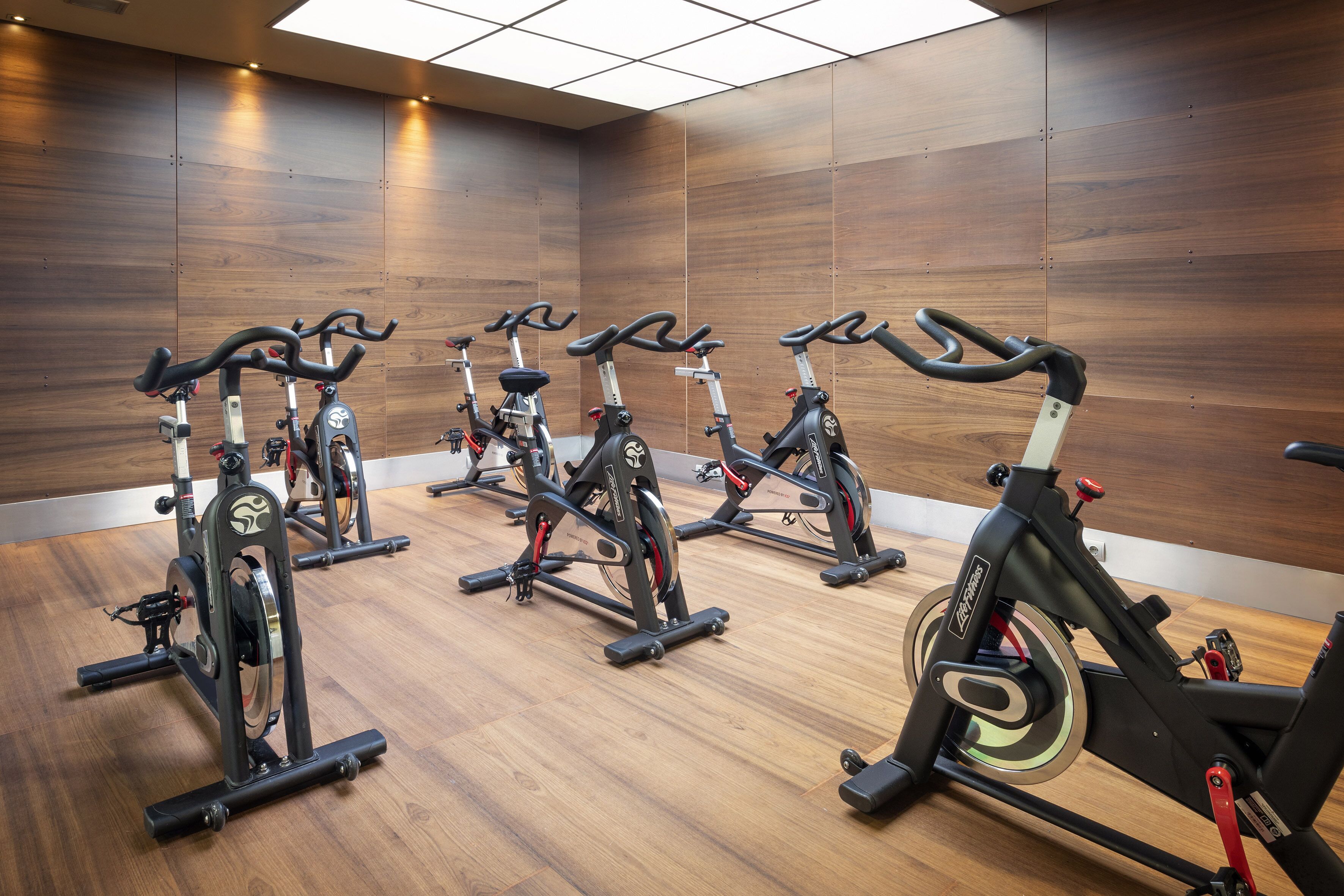 Une salle de sport équipée de plusieurs vélos d’appartement disposés en rangées.