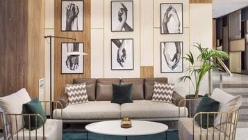 Ein modernes Wohnzimmer mit einer Couch, zwei Sesseln, einem Couchtisch und gerahmten Kunstwerken an der Wand.