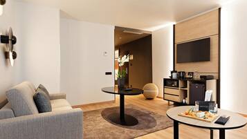 Una sala de estar moderna con un sofá, una mesa redonda de centro y un televisor de pantalla plana en la pared.