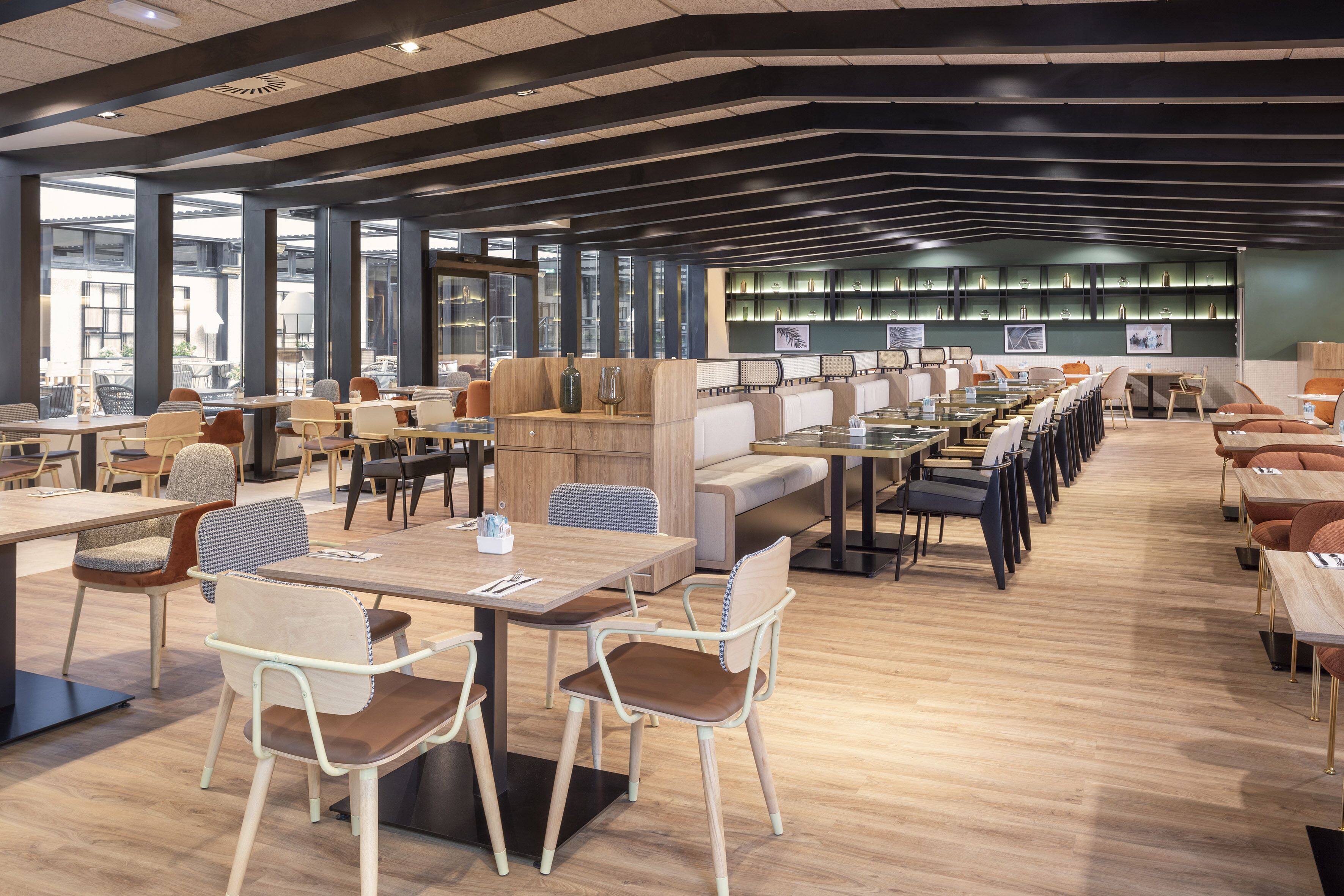 Una biblioteca moderna con varias zonas de descanso, incluyendo mesas y sillas, y una amplia estantería al fondo.