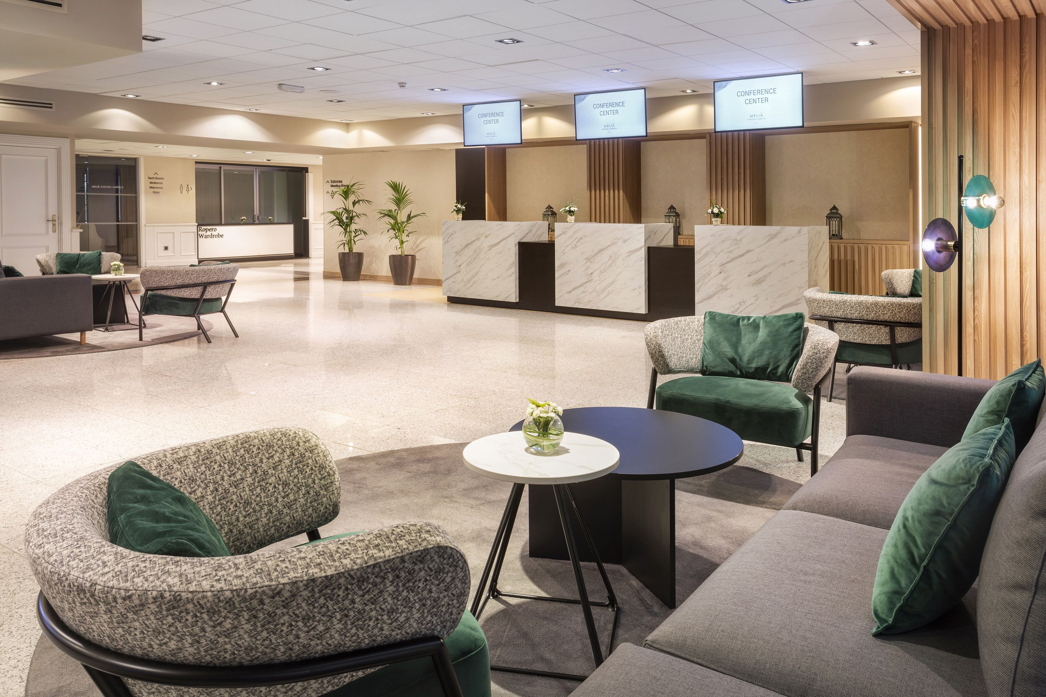 Un moderno vestíbulo de hotel con mostrador de recepción, zona de estar y centro de conferencias.