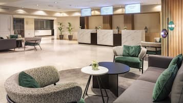 Un moderno vestíbulo de hotel con mostrador de recepción, zona de estar y centro de conferencias.