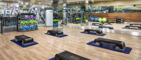 Une salle de sport équipée de matériel d’exercice, de miroirs et dotée d’un plancher en bois.