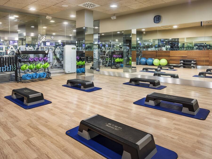 Ett gym med träningsutrustning, speglar och ett trägolv.