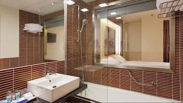 A bathroom with a large mirror, a sink, a shower, and a bathtub.