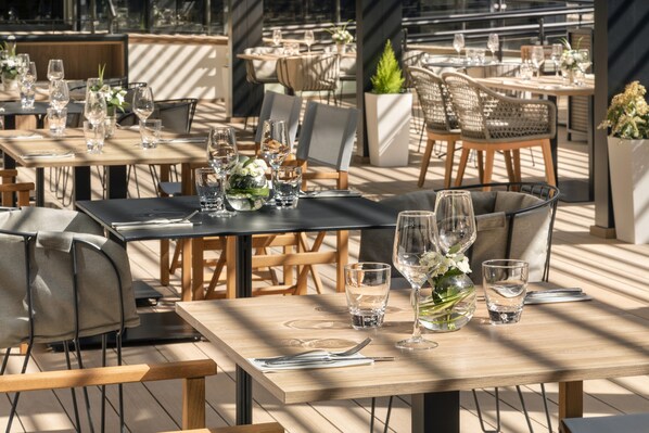 A restaurant with multiple tables set for dining, featuring a mix of chairs and benches. - Melia Avenida América (Madrid)