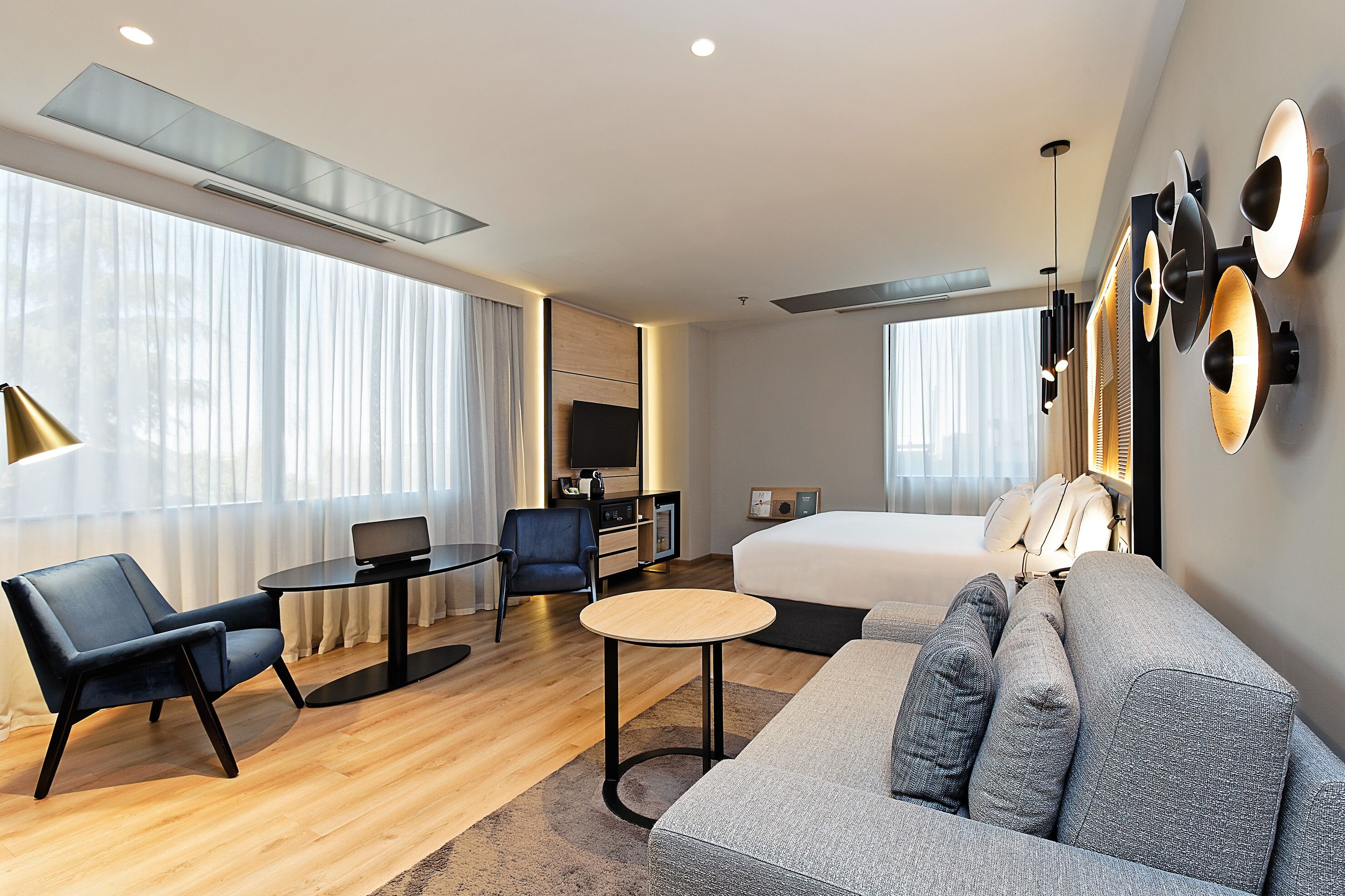 Una habitación de hotel moderna con sofá, escritorio, silla, cama y televisor.
