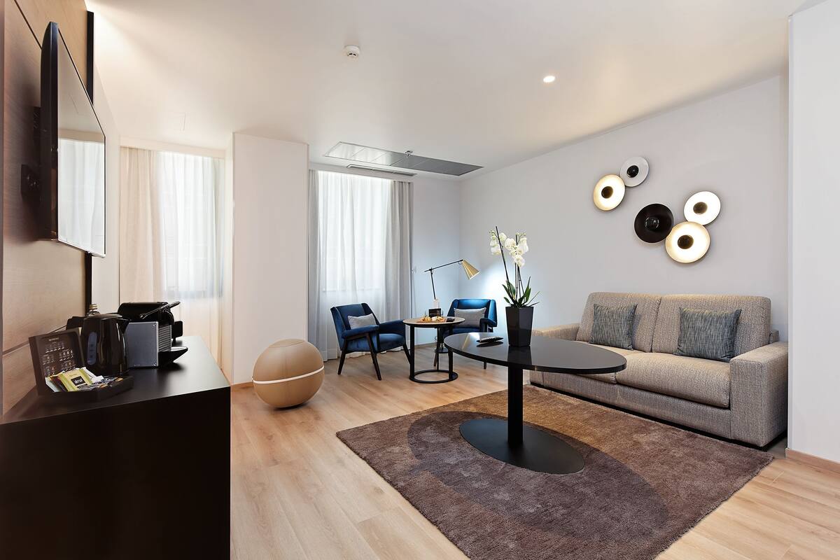 A modern living room with a sofa, chairs, a coffee table, and a TV.