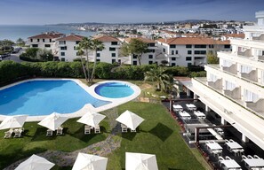 Un hotel con piscina, mobiliario exterior y vistas al mar.