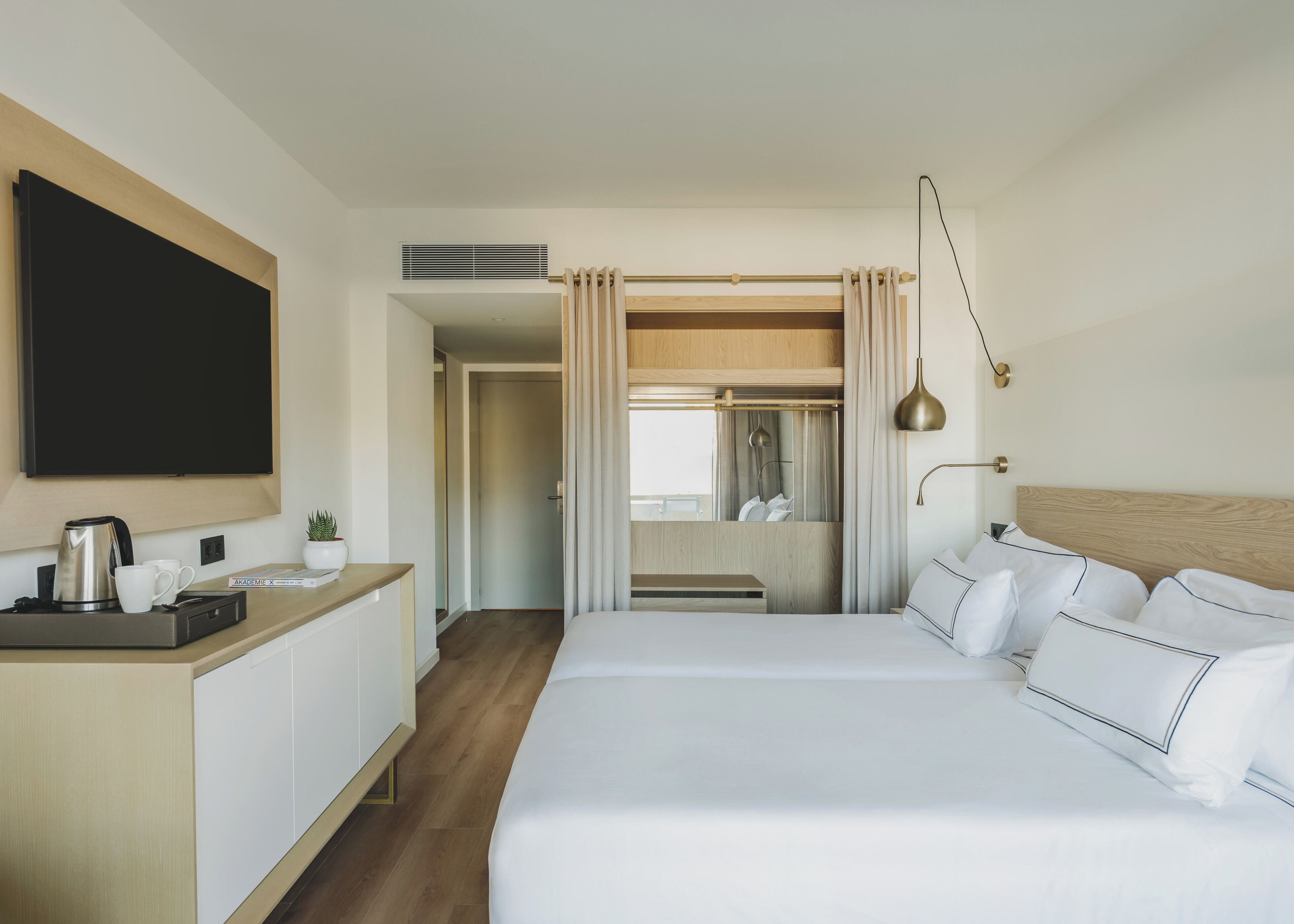 A hotel room with a bed, bedside table, TV, and a view of the bathroom.