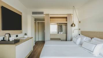 A hotel room with a bed, bedside table, TV, and a view of the bathroom.