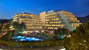 A multi-story hotel with a pool area, outdoor seating, and a well-lit facade. - Melia Sitges (Sitges)