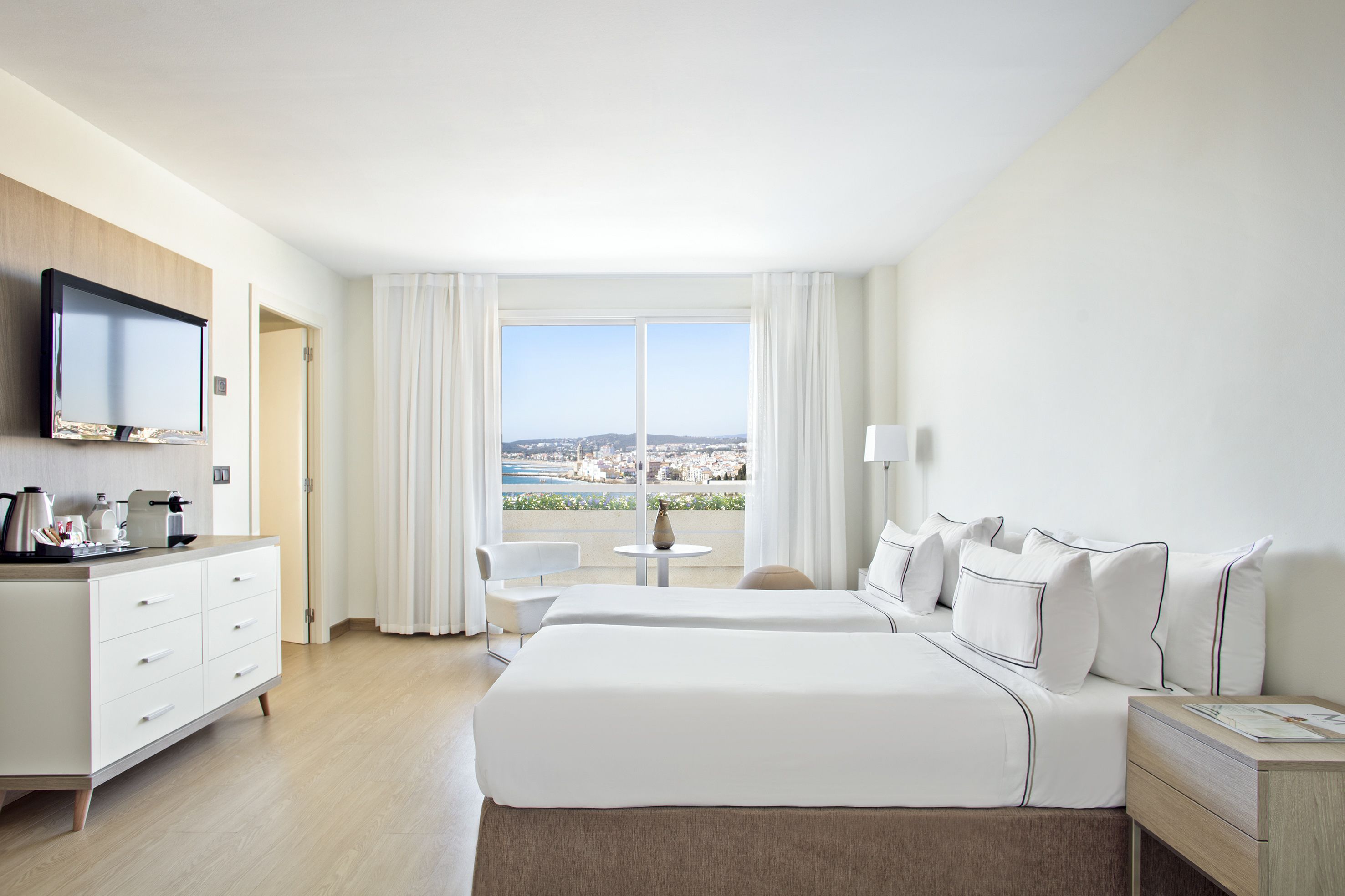Habitación de hotel con una cama grande, un escritorio, una silla y un televisor en la pared.