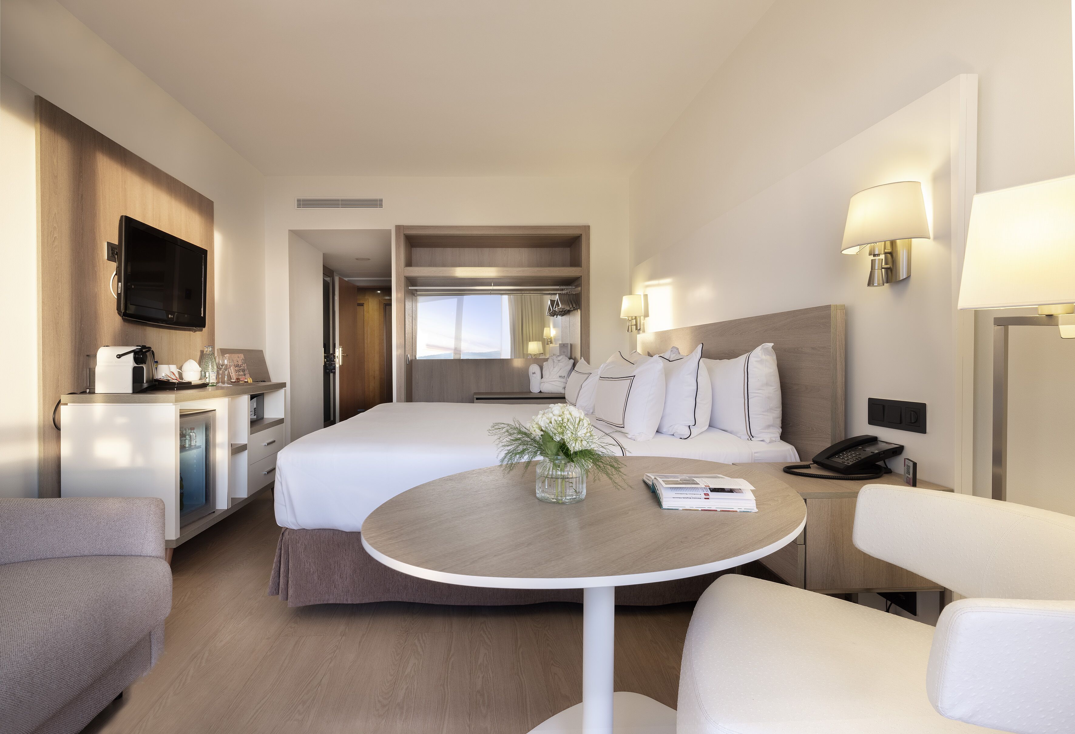 Una habitación de hotel con cama, escritorio, silla, mesa y televisor.
