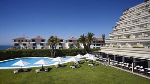 Un hotel con piscina, zona de estar al aire libre y vistas al mar.