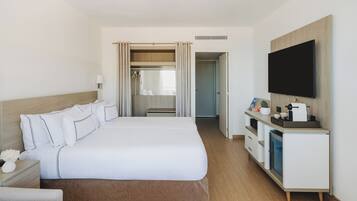 Une chambre d’hôtel avec un grand lit, une télévision, un bureau avec une machine à café et un dressing.