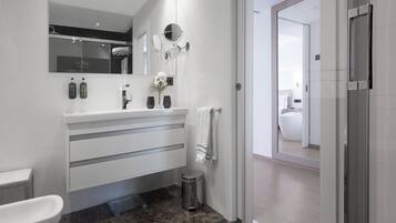 A modern bathroom with a white vanity, a large mirror, and a glass shower enclosure.