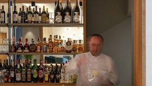 Zona de bar con estantes llenos de botellas de licor y vasos.