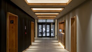 Un pasillo moderno de hotel con paneles de madera, un mostrador de recepción y una entrada de vidrio.