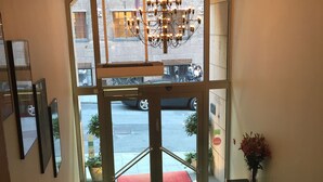 A hotel entrance with a large arched glass door, a chandelier, a red carpet, and a staircase leading to the entrance. - ProfilHotels Riddargatan (Stockholm)