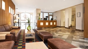 A modern lobby with leather sofas, a reception desk, and a patterned carpet. - ProfilHotels Riddargatan (Stockholm)