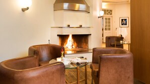A cozy living room with leather armchairs, a glass coffee table, and a fireplace. - ProfilHotels Riddargatan (Stockholm)