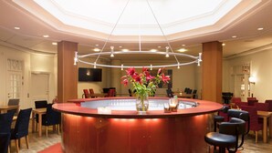 A hotel lobby with a central bar area, seating arrangements, and a large skylight. - ProfilHotels Riddargatan (Stockholm)