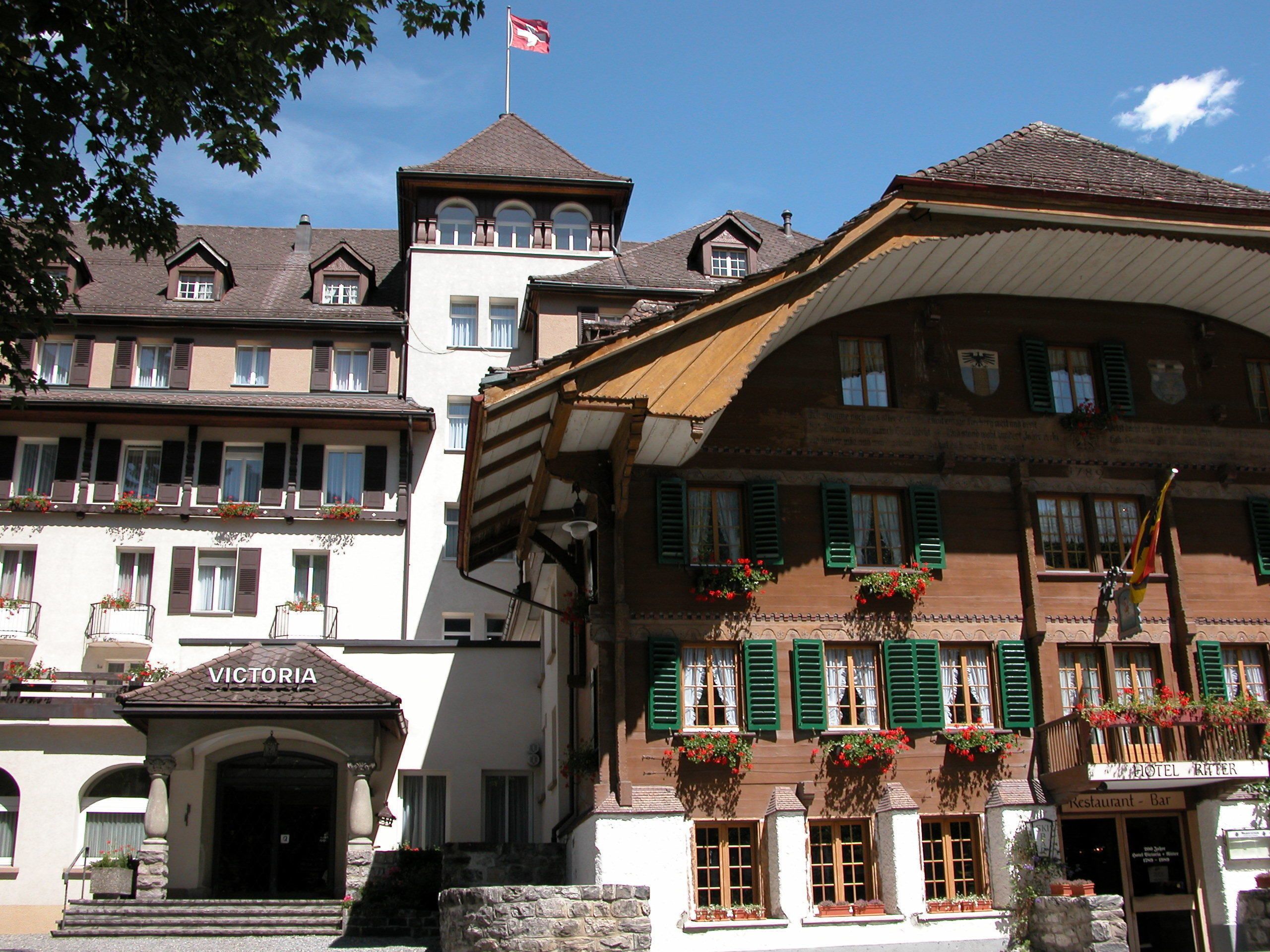 A traditional European hotel with a prominent entrance, multiple windows with shutters, and flower boxes.