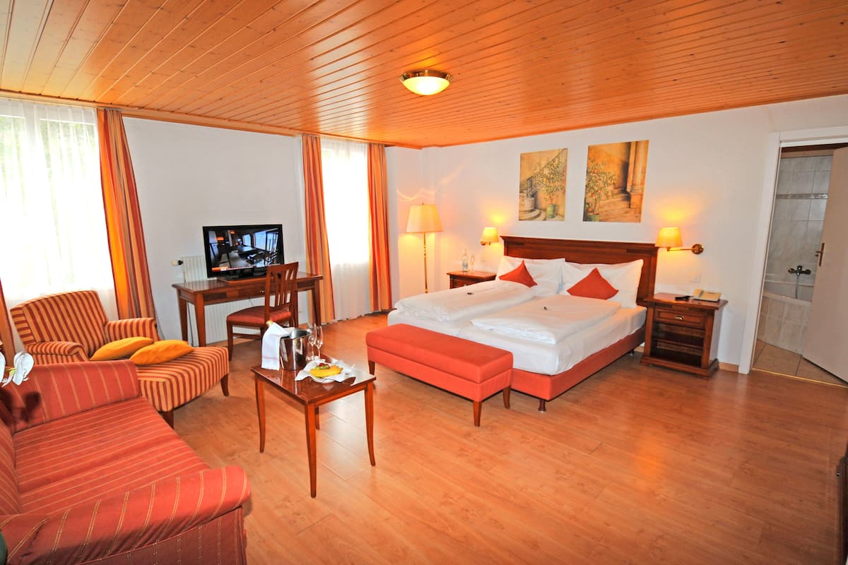 Ein Hotelzimmer mit Bett, einer Couch, einem Fernseher und einem Schreibtisch mit Lampe.