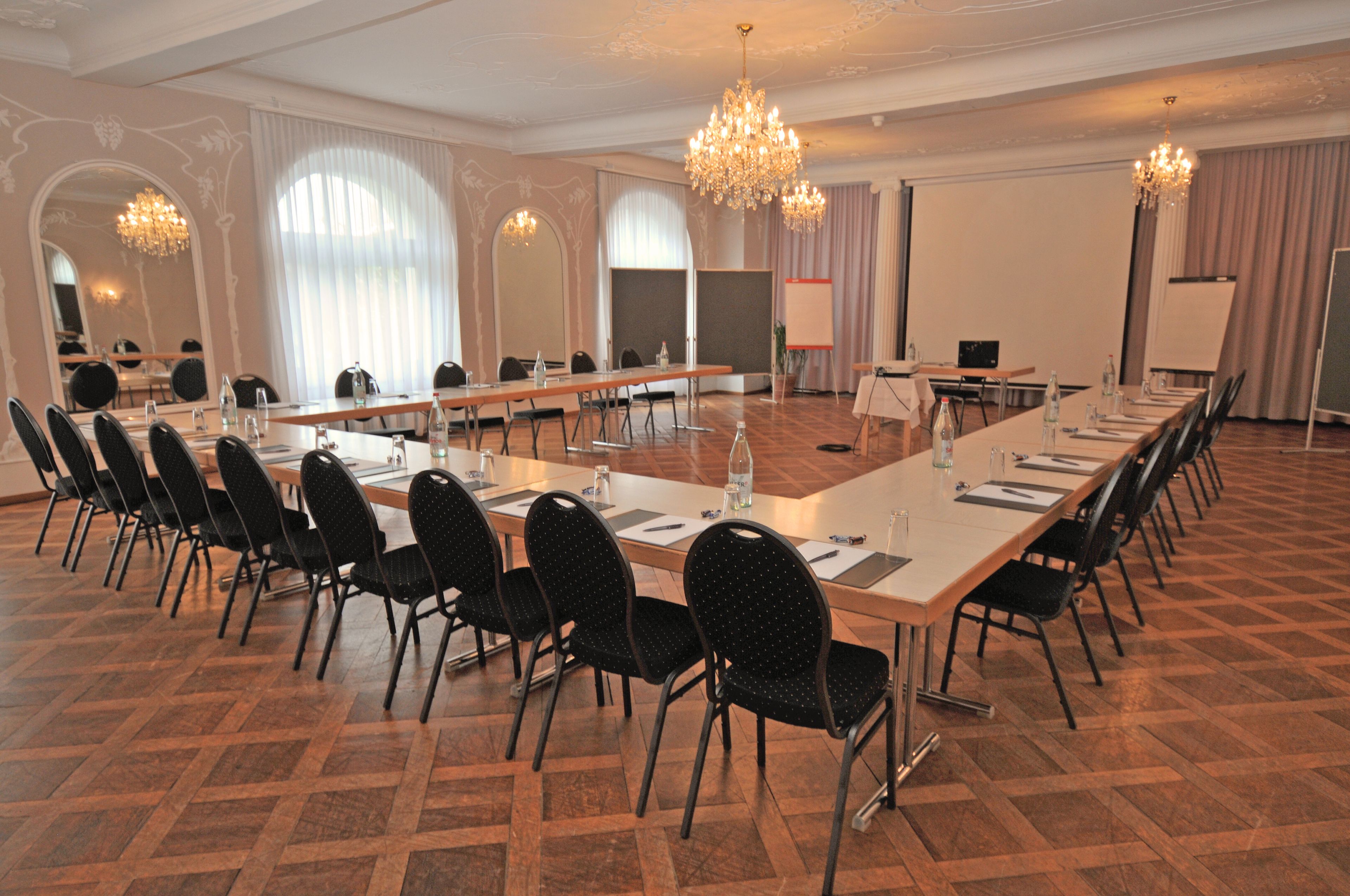 A conference room with a long table, chairs, and a projector screen.