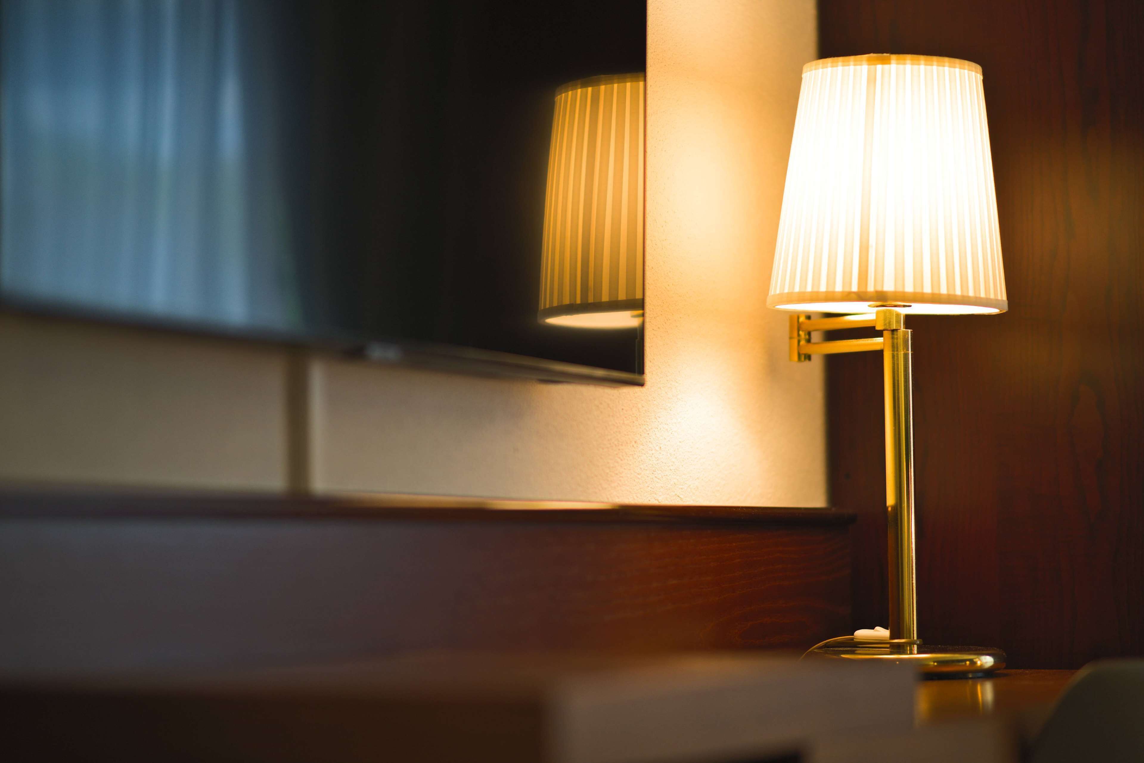 Une lampe avec un abat-jour à motifs en relief, posée sur une surface en bois.