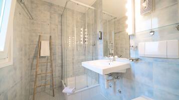 A modern bathroom with a glass-enclosed shower, a white sink, and a glass shower door.