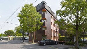 Un edificio moderno con techo plano, varias ventanas y un letrero que indica un hotel.