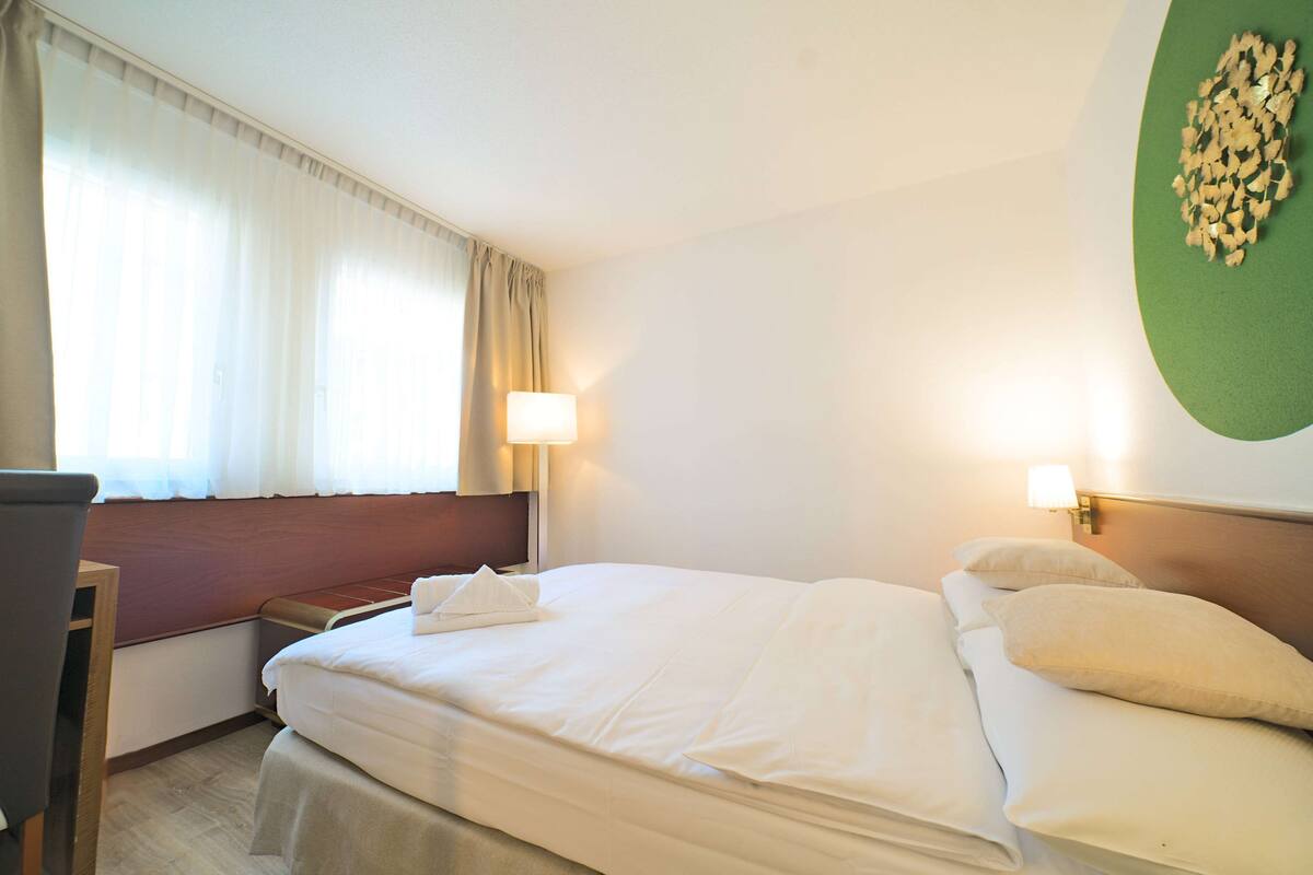 Ein Hotelzimmer mit Bett, Schreibtisch, Lampe und Wanddekoration.