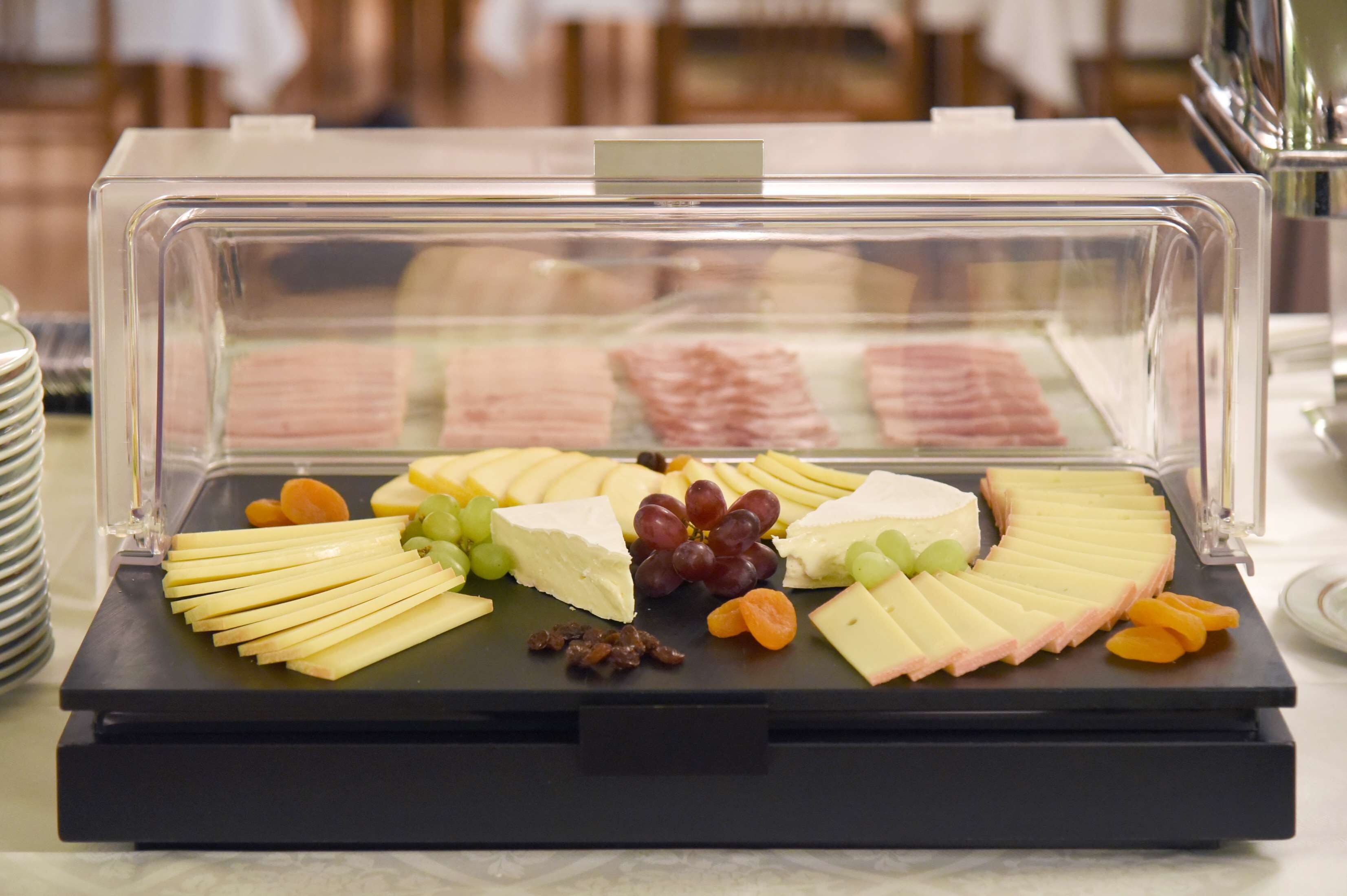 A cheese and fruit platter in a clear display case.