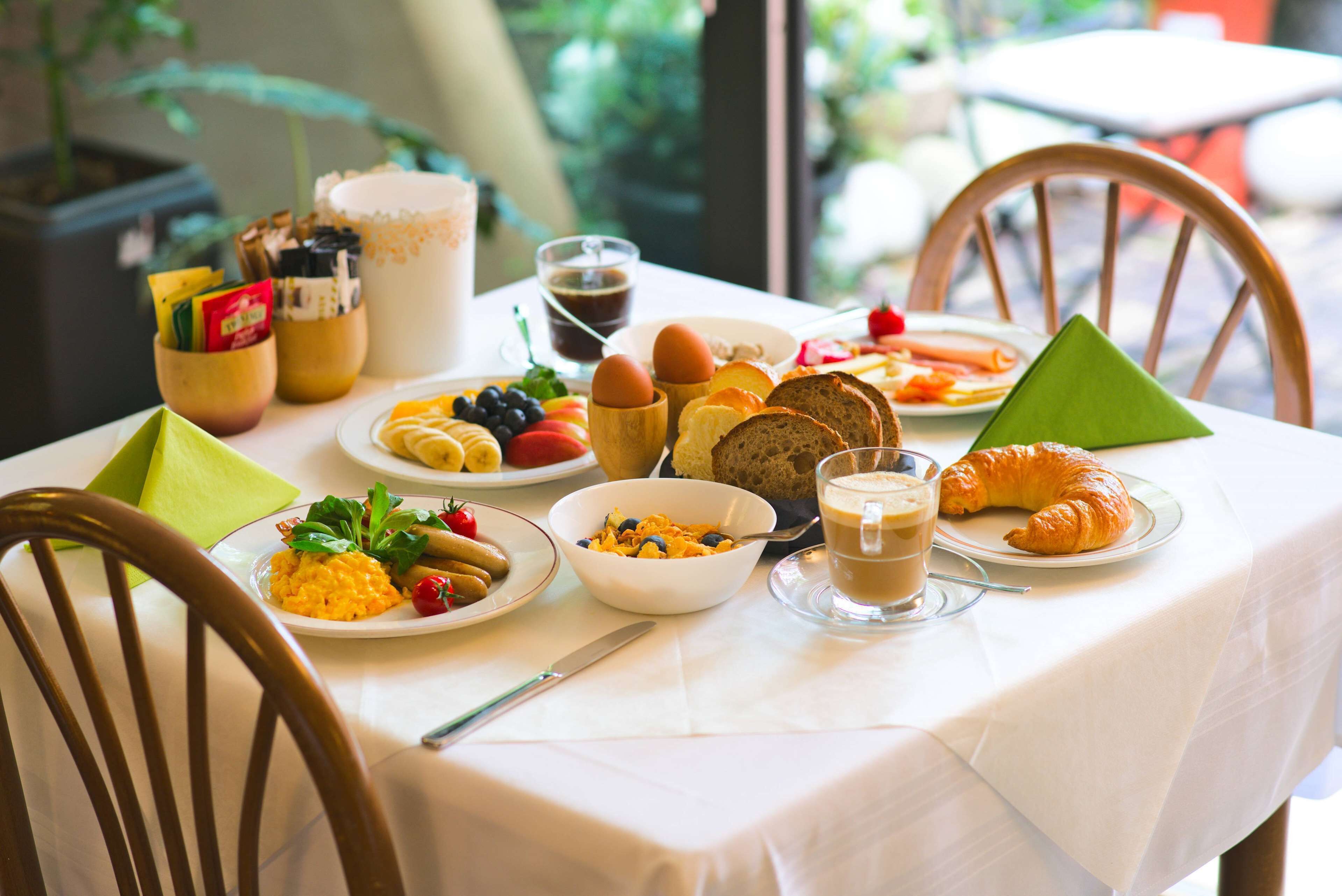 A breakfast table with various food items, including croissants, fruits, and beverages.