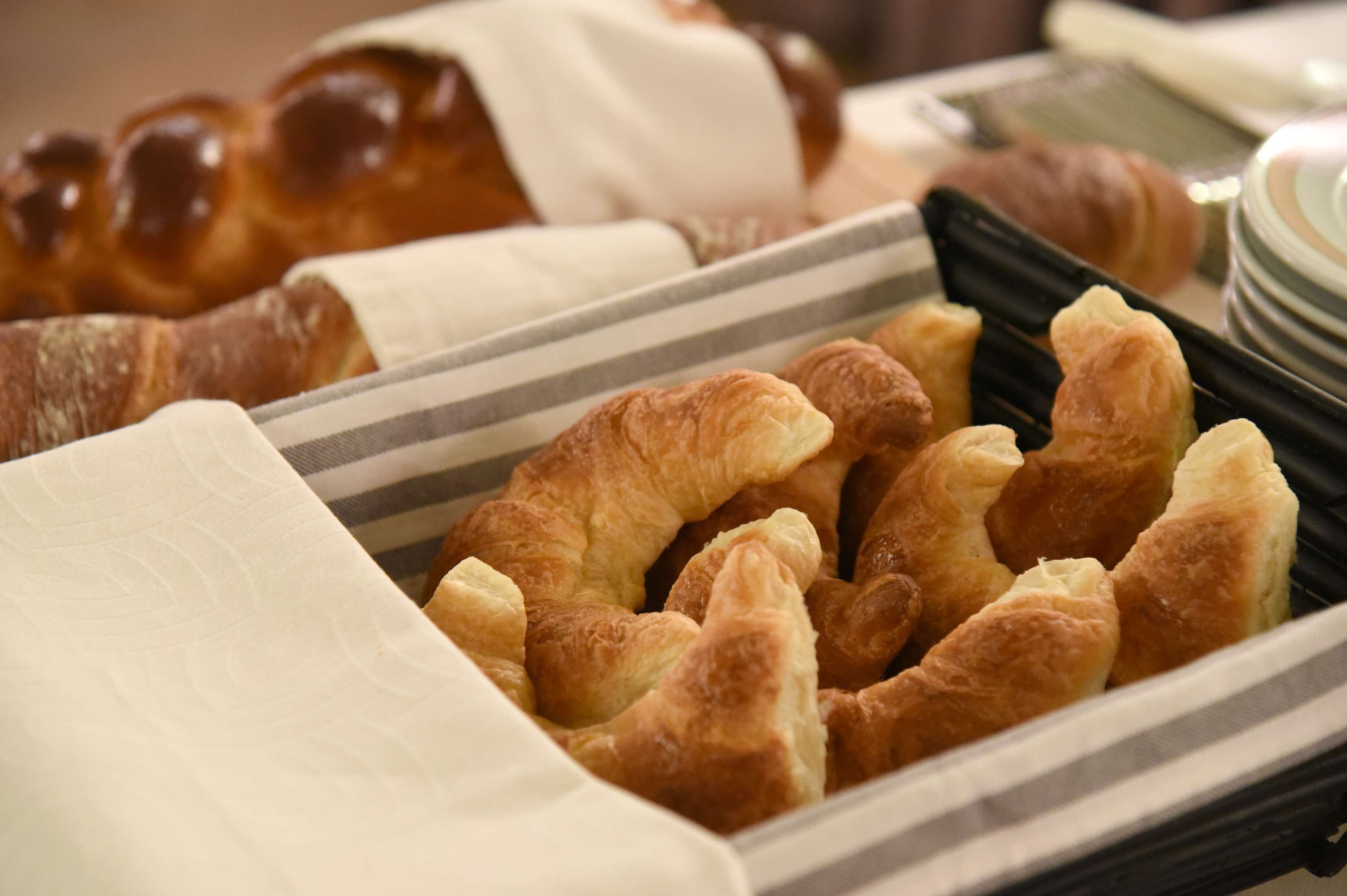 A tray of assorted pastries including croissants and a loaf of bread.
